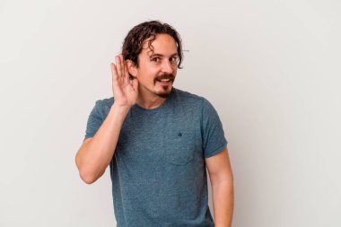 Beyaz arka planda izole edilmiş genç beyaz adam bir dedikoduyu dinlemeye çalışıyor..