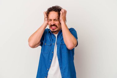 Beyaz arka planda izole edilmiş genç beyaz bir adam kulaklarını elleriyle kapatıyor..