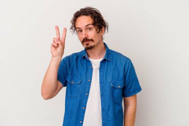 Beyaz arka planda izole edilmiş genç beyaz bir adam neşeli ve kaygısız parmakları olan bir barış sembolü gösteriyor..