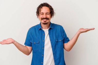 Beyaz arka planda izole genç beyaz adam kollarıyla ölçek yapar, mutlu ve kendinden emin hisseder..