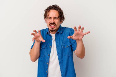 Beyaz arka planda izole edilmiş genç beyaz bir adam pençelerini kedi taklidi yaparken gösteriyor, agresif bir hareket..