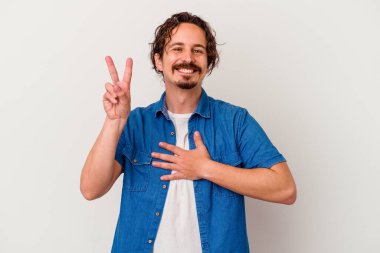 Beyaz arka planda izole edilmiş genç beyaz adam yemin ediyor, elini göğsüne koyuyor..