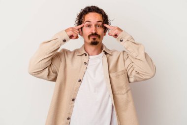 Beyaz arka planda izole edilmiş genç beyaz bir adam bir göreve odaklanmış, işaret parmaklarını işaret ediyor..