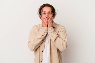 Beyaz arka planda izole edilmiş genç beyaz adam elleriyle ağzını kapatırken şok oldu..