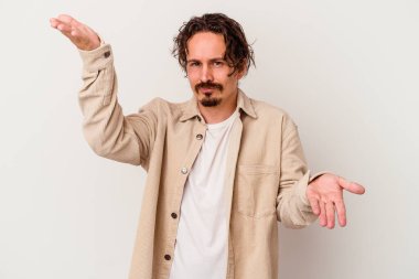 Beyaz arka planda izole genç beyaz adam kollarıyla ölçek yapar, mutlu ve kendinden emin hisseder..