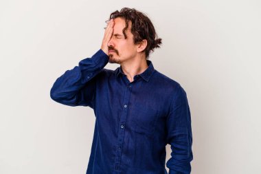 Beyaz arka planda izole olmuş genç beyaz bir adam başı ağrıyor, yüzüne dokunuyor..