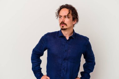 Beyaz arka planda izole edilmiş genç beyaz adam gülümseyen, neşeli ve keyifli bir tarafa bakıyor..