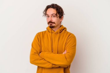 Beyaz arka planda izole edilmiş genç beyaz adam alaycı bir ifadeyle kameraya bakıyor..