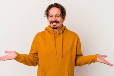 Beyaz arka planda izole genç beyaz adam kollarıyla ölçek yapar, mutlu ve kendinden emin hisseder..