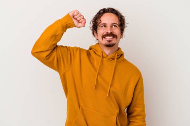 Beyaz arka planda izole edilmiş genç beyaz bir adam zaferi, tutkuyu ve coşkuyu kutluyor, mutlu bir ifade..