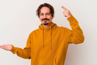 Beyaz arka planda izole edilmiş genç beyaz bir adam elinde bir ürün tutuyor ve.