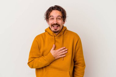 Beyaz arka planda izole genç beyaz adam yüksek sesle gülüyor elini göğsüne koyuyor..