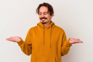 Beyaz arka planda izole edilmiş genç beyaz bir adam elinde avuç içi bir şeyle kameraya sunuyor..