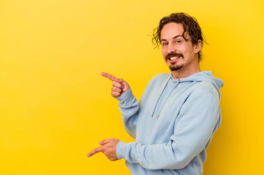 Sarı arka planda izole edilmiş genç beyaz adam işaret fişekleriyle işaret ederek heyecanlanıyor..