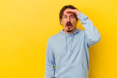 Sarı arka planda izole edilmiş genç beyaz adam yüksek sesle bağırıyor, gözleri açık ve elleri gergin tutuyor..