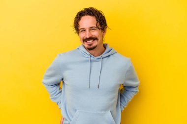 Sarı arka planda izole edilmiş genç beyaz adam mutlu, güler yüzlü ve neşeli..