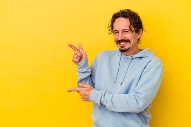 Sarı arka planda izole edilmiş genç beyaz adam işaret parmağıyla fotokopi alanını işaret ederek heyecan ve arzusunu ifade ediyor..