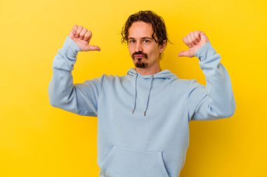 Sarı arka planda izole edilmiş genç beyaz adam gururlu ve kendinden emin hissediyor, örnek olarak.