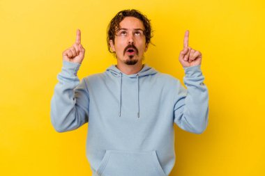 Sarı arka planda izole edilmiş beyaz bir adam ağzı açık bir şekilde üst tarafı işaret ediyor..
