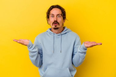 Sarı arka planda izole edilmiş genç beyaz adam şaşırdı ve şok oldu..