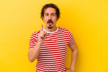 Sarı arka planda izole edilmiş genç beyaz adamın bir fikri var, ilham verici bir kavram..