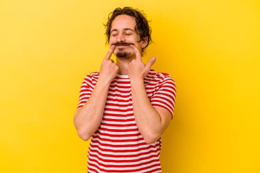 Kafkasyalı genç, sarı arka planda izole edilmiş, iki seçenek arasında şüphe duyuyor..