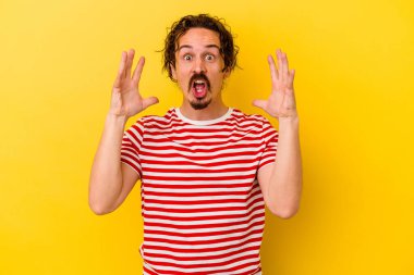 Sarı arka planda izole edilmiş genç beyaz bir adam zaferi ya da başarıyı kutluyor, şaşırıyor ve şok oluyor..