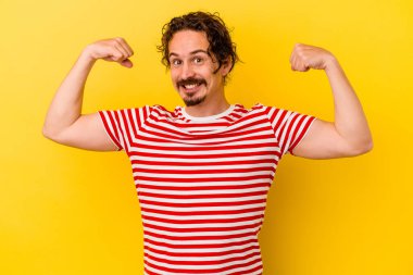 Sarı arka planda izole edilmiş genç beyaz adam güçlü bir hareket sergiliyor, kadınsı gücün sembolü.