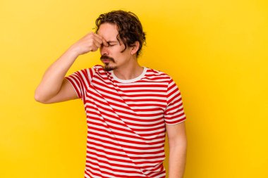 Kafkasyalı genç adam sarı arka planda izole edilmiş, başı ağrıyor, yüzüne dokunuyor..