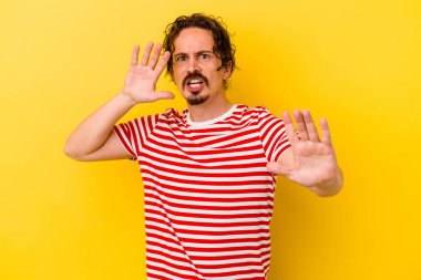 Sarı arka planda izole genç beyaz adam yakın bir tehlike nedeniyle şoka uğruyor