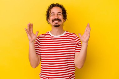 Sarı arka planda izole edilmiş genç beyaz bir adam neşeli bir şekilde gülüyor. Mutluluk kavramı.