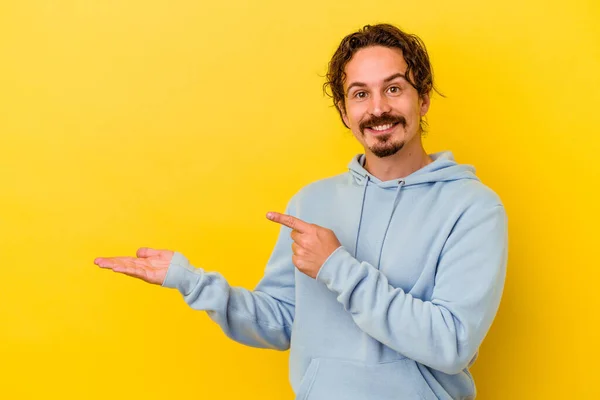 Jovem Caucasiano Isolado Fundo Amarelo Animado Segurando Espaço Cópia Palma — Fotografia de Stock