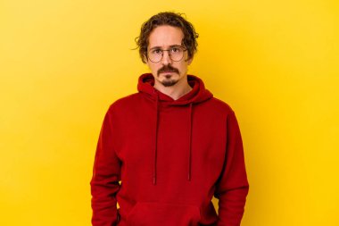 Kafkasyalı genç adam sarı arka planda izole edilmiş üzgün, ciddi yüzlü, mutsuz ve hoşnutsuz..