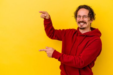 Sarı arka planda izole edilmiş genç beyaz adam işaret fişekleriyle işaret ederek heyecanlanıyor..