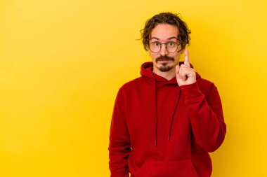 Sarı arka planda izole genç beyaz adam parmak ile bir numara gösteriyor.