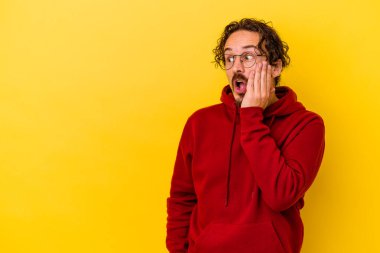 Sarı arka planda izole edilmiş genç beyaz adam gördüğü bir şey yüzünden şoka uğruyor..