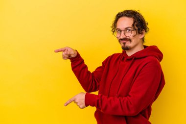 Sarı arka planda izole edilmiş genç beyaz adam işaret parmağıyla fotokopi alanını işaret ederek heyecan ve arzusunu ifade ediyor..