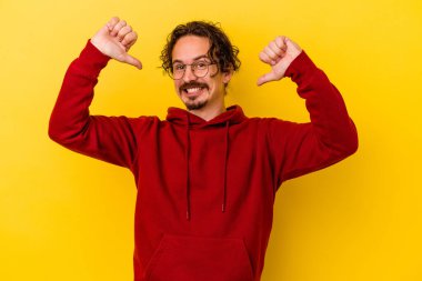 Sarı arka planda izole edilmiş genç beyaz adam gururlu ve kendinden emin hissediyor, örnek olarak.