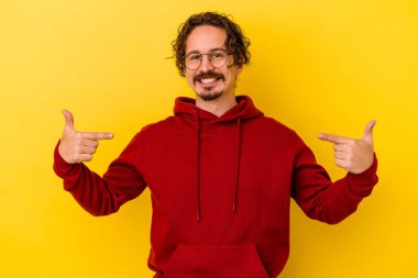 Sarı arka planda izole edilmiş genç beyaz adam parmakları aşağıda, olumlu bir his var..