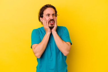 Sarı arka planda izole edilmiş genç beyaz adam korkmuş ve korkmuş..