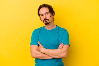 Sarı arka planda izole edilmiş genç beyaz adam sıkılmış, yorgun ve dinlenmeye ihtiyacı var..