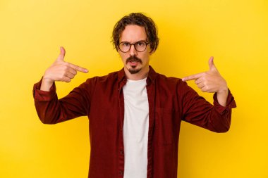 Sarı arka planda izole edilmiş genç beyaz adam parmakları aşağıda, olumlu bir his var..