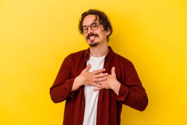 Sarı arka planda izole edilmiş beyaz bir genç, dost canlısı bir ifadeye sahip, avuçlarını göğsüne bastırıyor. Aşk konsepti.