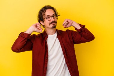 Sarı arka planda izole edilmiş, kollarını uzatan, rahat bir pozisyonda genç beyaz bir adam..