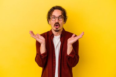 Sarı arka planda izole edilmiş genç beyaz adam şaşırdı ve şok oldu..