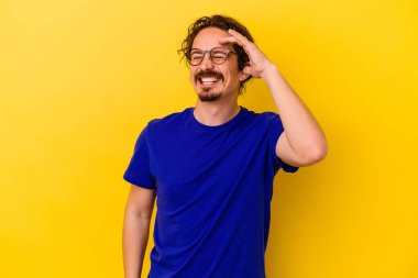 Sarı arka planda izole edilmiş genç beyaz bir adam neşeli bir şekilde gülüyor. Mutluluk kavramı.