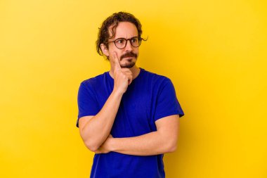 Kafkasyalı genç bir adam sarı arka planda izole edilmiş. Bir strateji planlıyor, bir iş yolu düşünüyor..