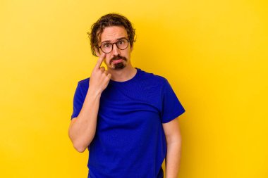 Kafkasyalı genç adam sarı arka planda izole edilmiş, ağlıyor, bir şeyden memnun değil, acı ve kafa karışıklığı kavramı..