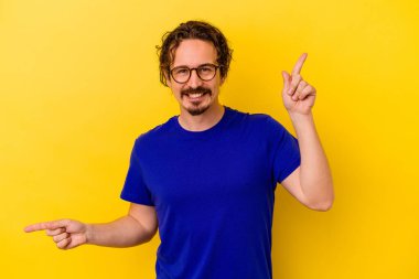 Sarı arka planda izole edilmiş genç beyaz adam farklı kopya alanlarını gösteriyor, birini seçiyor, parmağıyla gösteriyor..