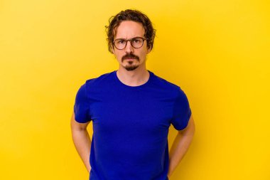 Kafkasyalı genç adam sarı arka planda izole edilmiş üzgün, ciddi yüzlü, mutsuz ve hoşnutsuz..